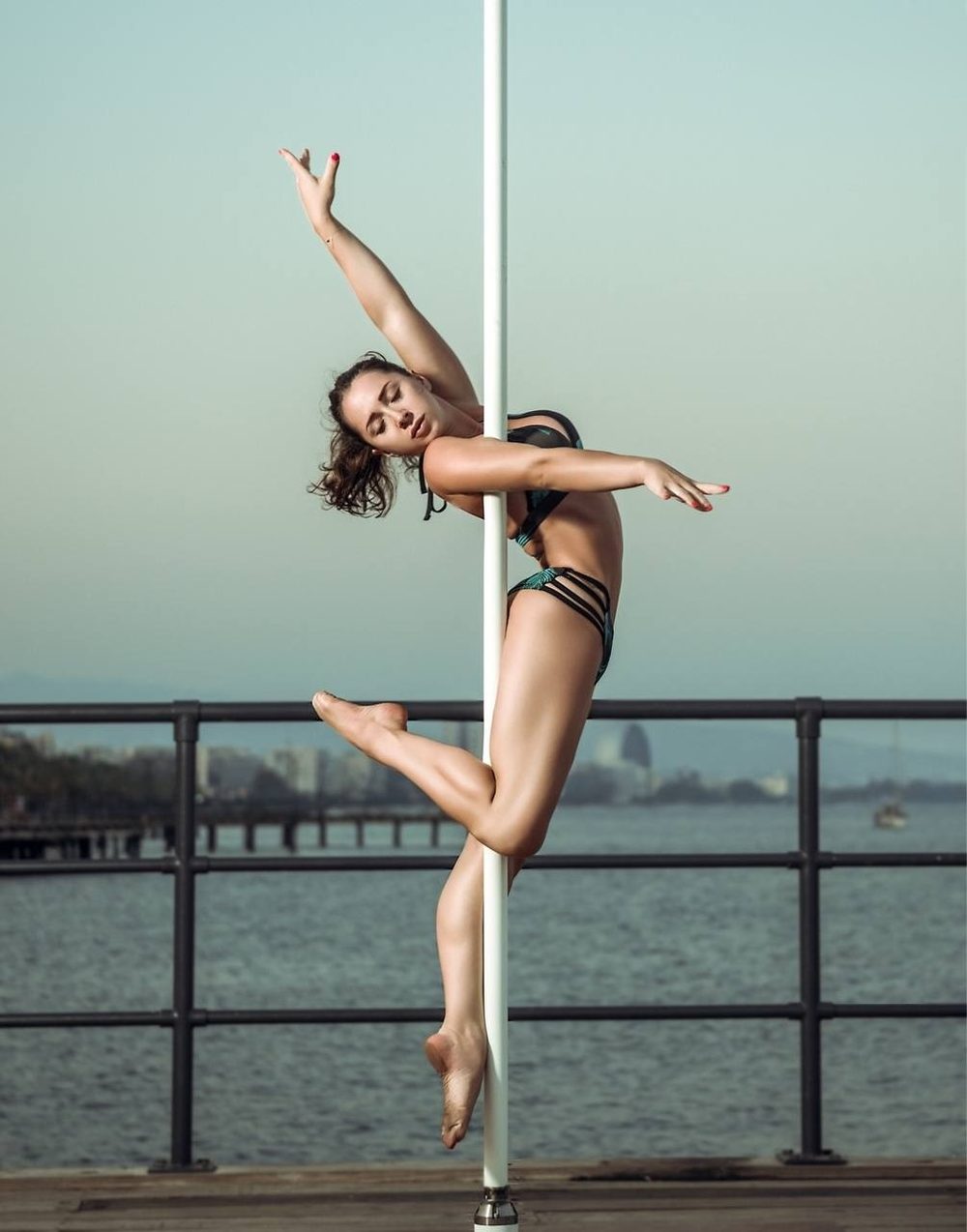 Olga, founder of Bodyflow, in a pole pose by the sea in Limassol